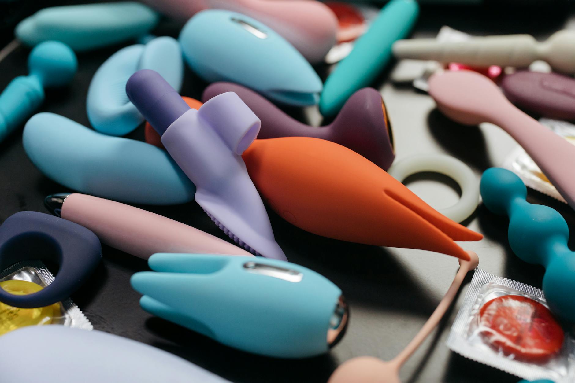 Hand holding a vibrant clitoral vibrator against a purple backdrop