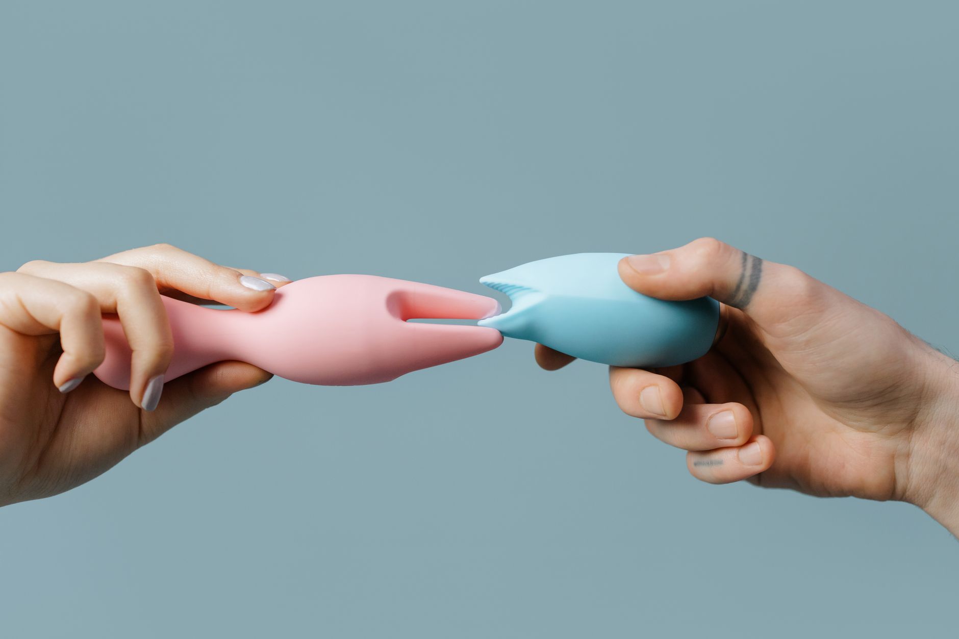 Hand holding an orange vibrator against a minimalistic purple backdrop
