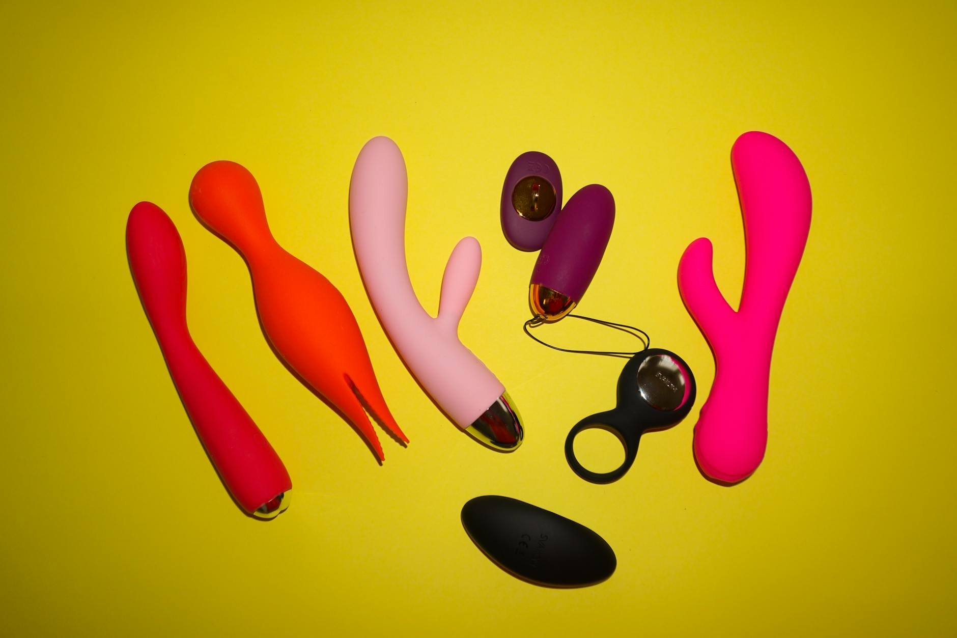 Colorful clitoral vibrators and personal massagers arranged on a bright yellow background